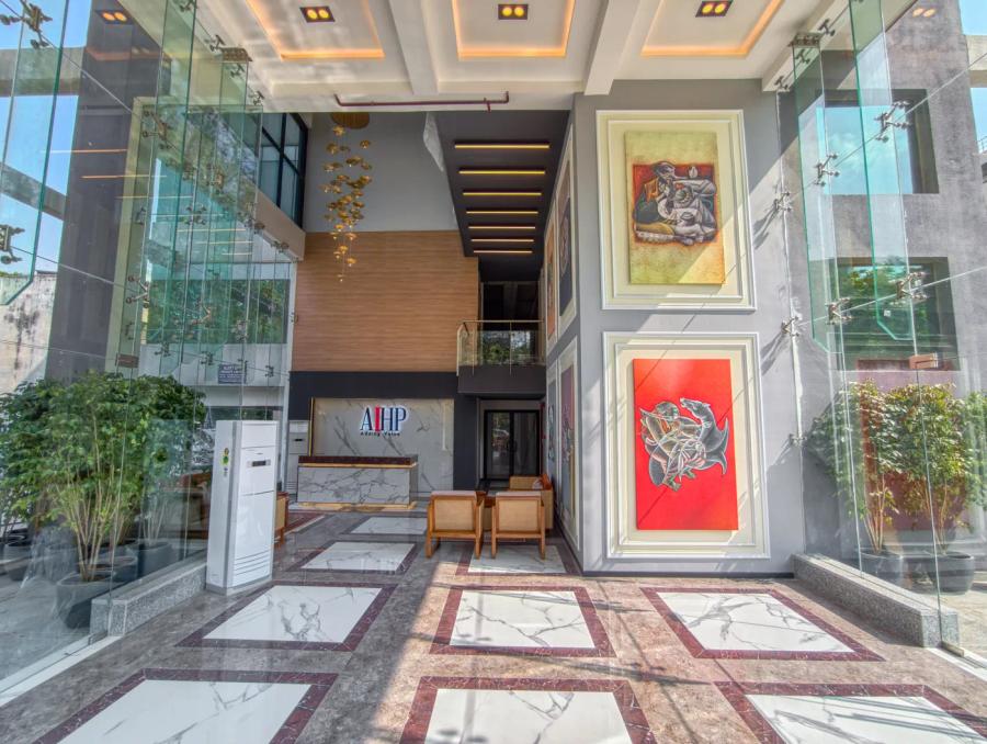 AIHP Atrium double-height lobby with backlit art wall and AIHP brand signage over marble flooring, Sector 32 Gurgaon