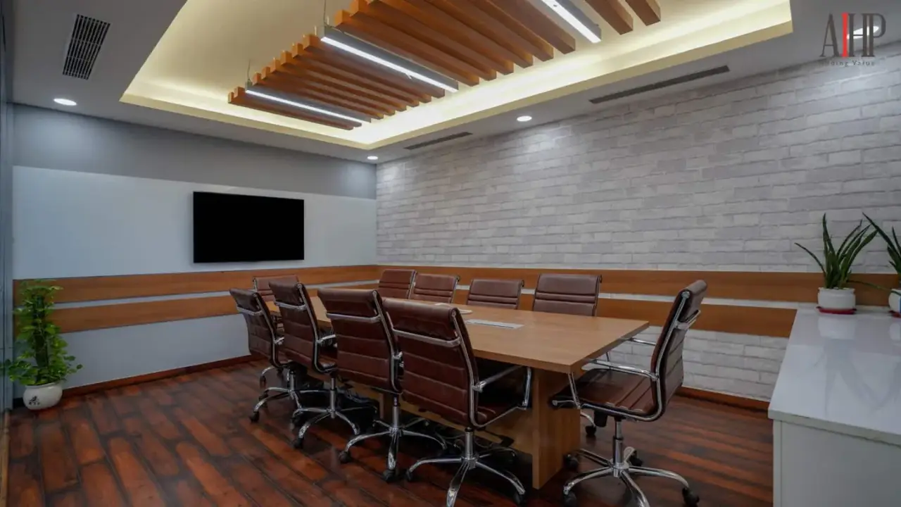 Boardroom with a long table, leather chairs and a wall-mounted screen under a wood ceiling panel, in an AIHP managed office in Gurgaon