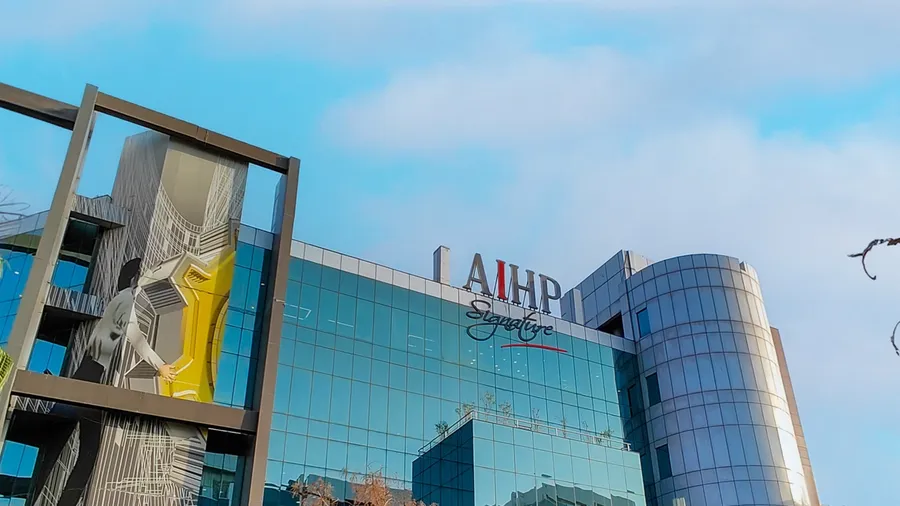 Glass facade of AIHP Signature office building with signage and a street-art mural