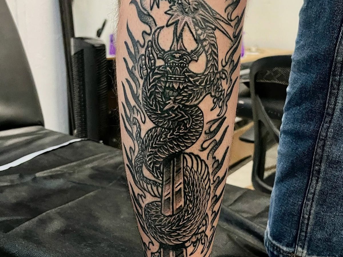 Traditional Japanese dragon forearm piece featuring detailed scales, flames, and ornamental elements in black and grey.