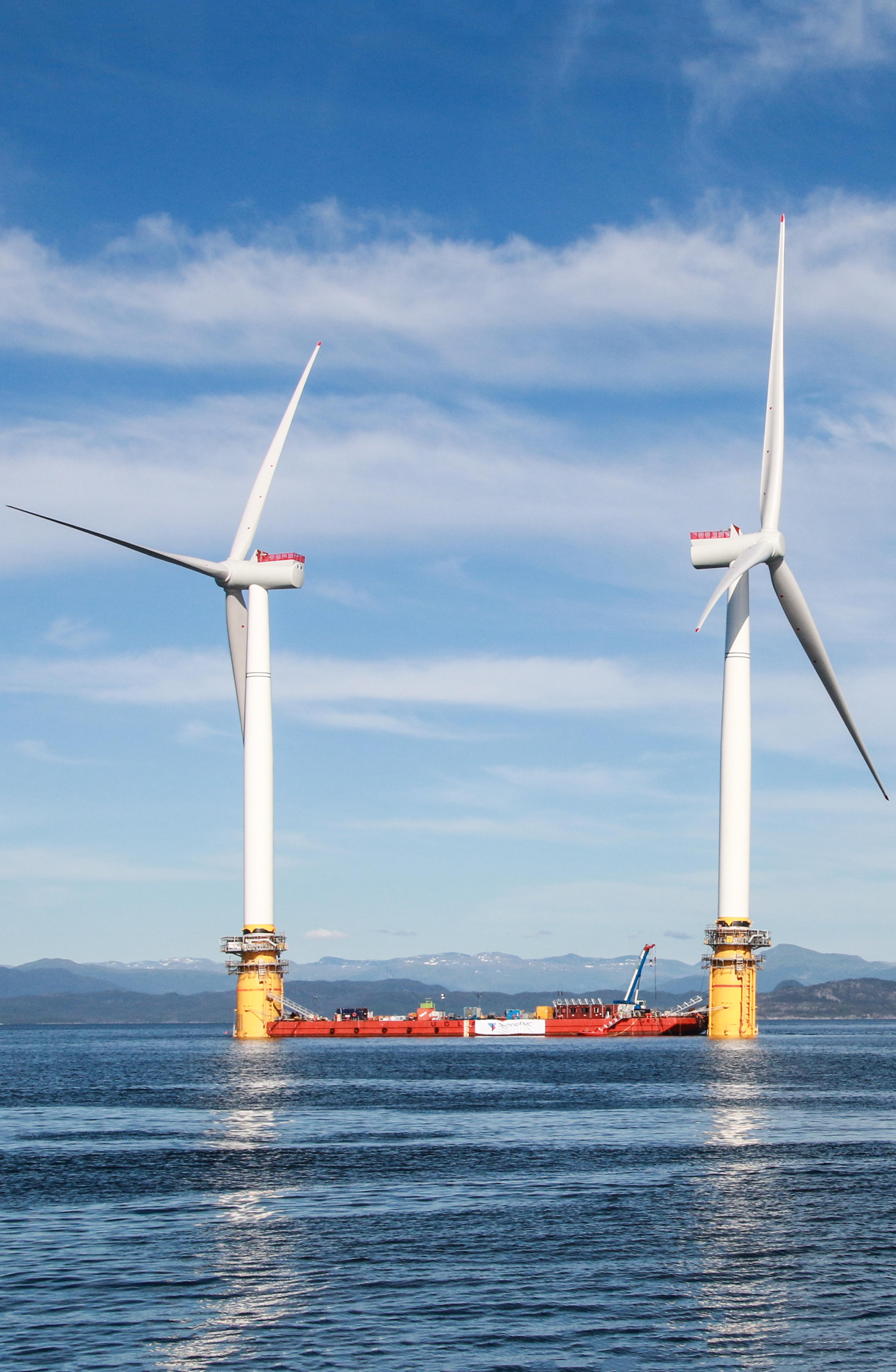 a picture of two floating wind turbines being prepared to sail
