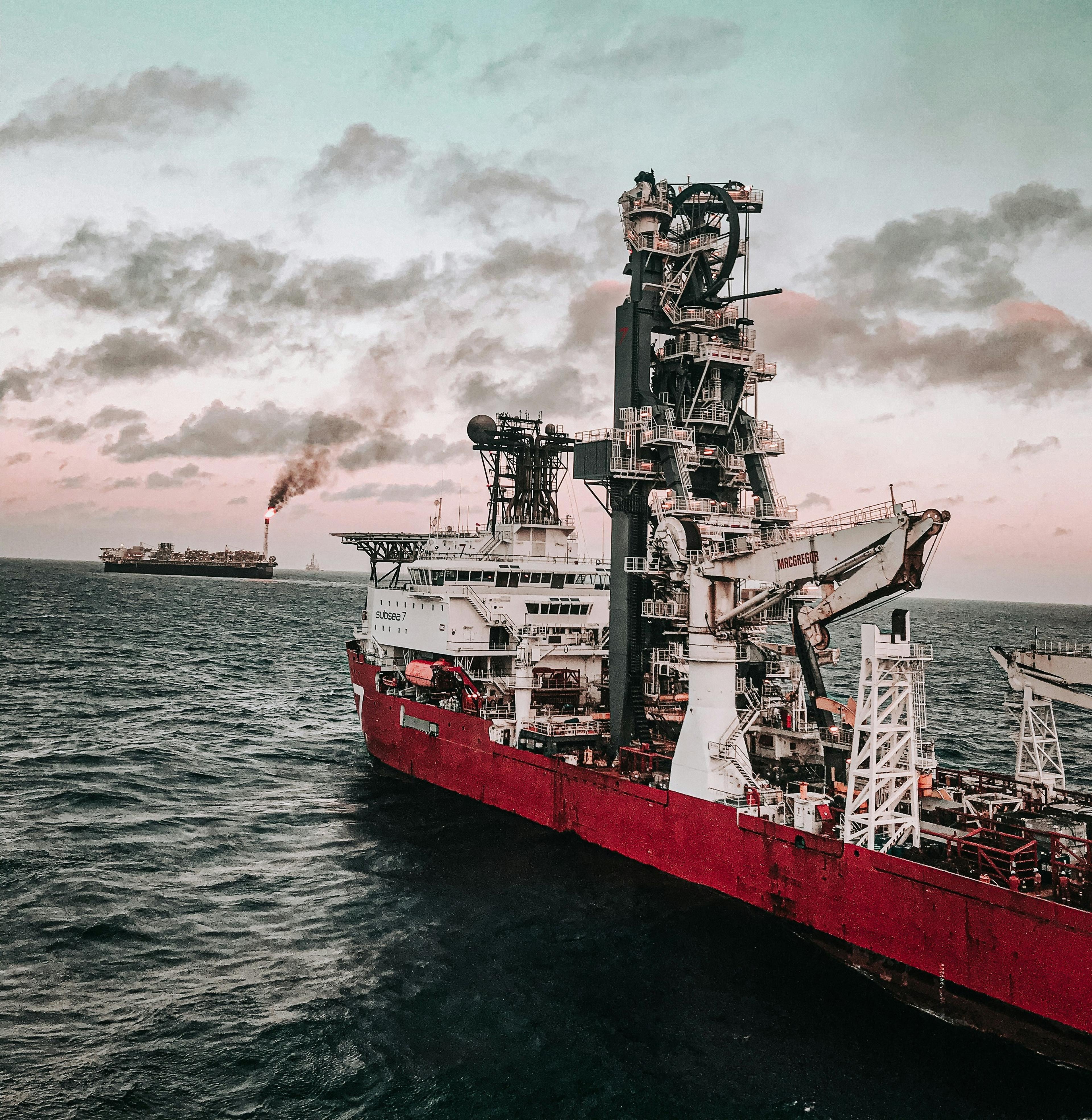 A red ship with a helideck navigating towards an FPSO
