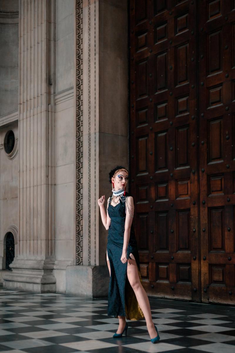 Editorial portrait of a woman in a dark dress near tall wooden doors