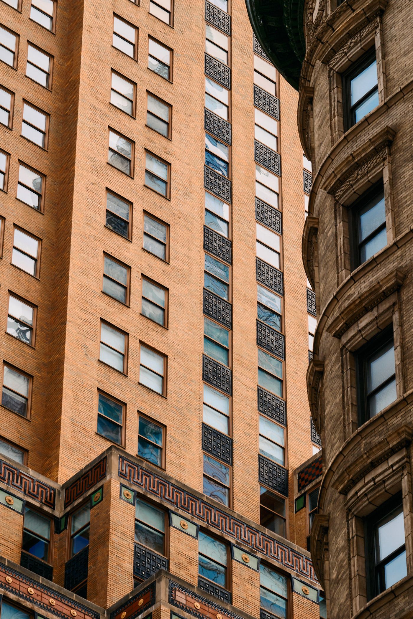 Two tall buildings with many windows, a clock on the left side, and a traffic light on the right side.