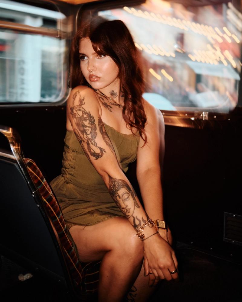 Tattooed woman posing in a diner booth with blurred neon reflections