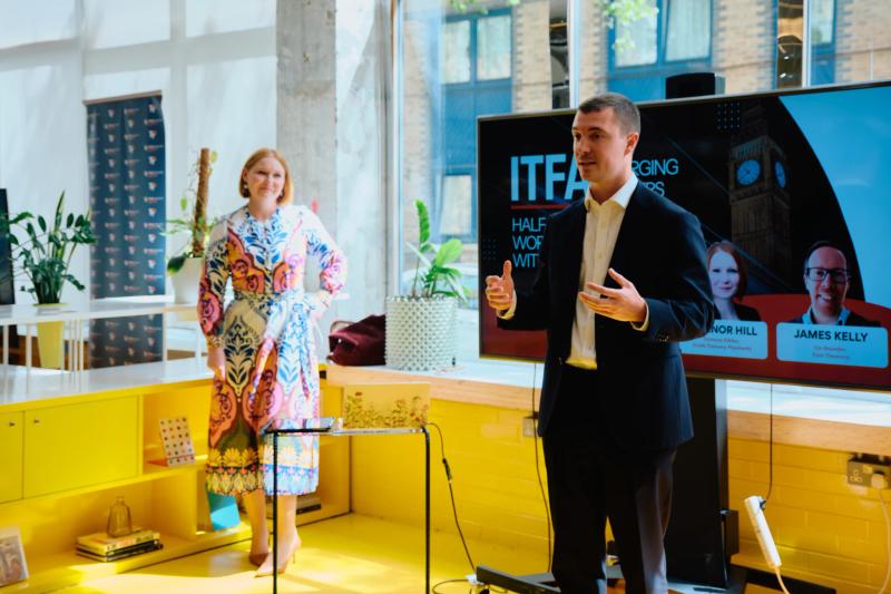 A man in a suit is giving a presentation in front of a woman.