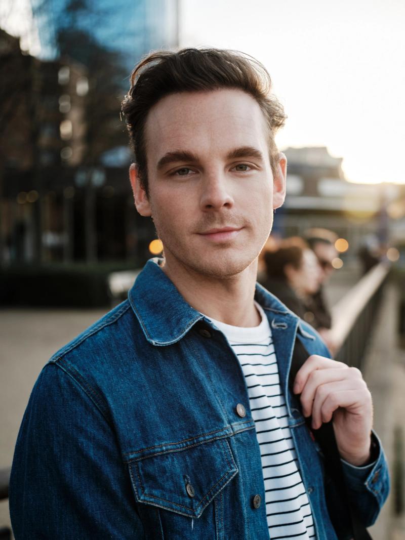 Close portrait of a man in a denim jacket and striped shirt by the waterfront