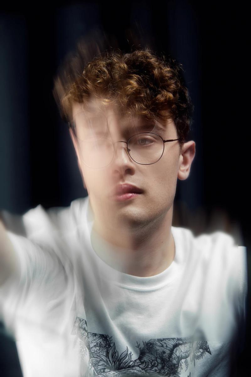 A man with glasses and red hair is wearing a white shirt.