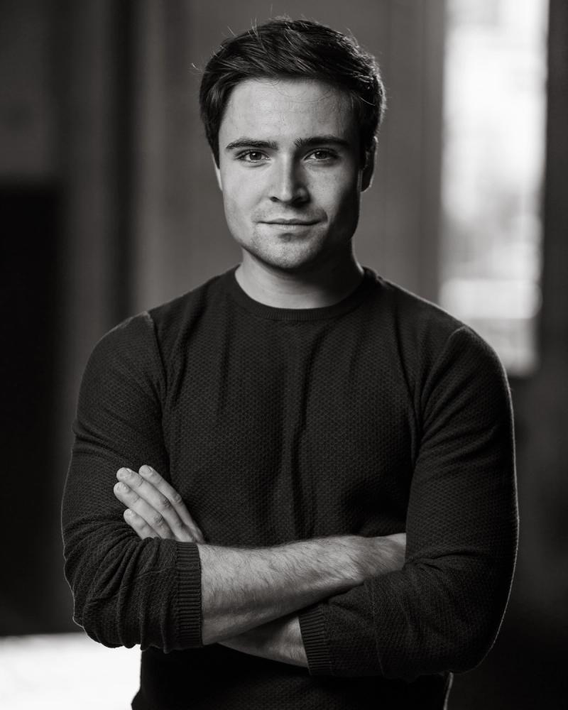 Black-and-white studio portrait of a man in a fitted turtleneck