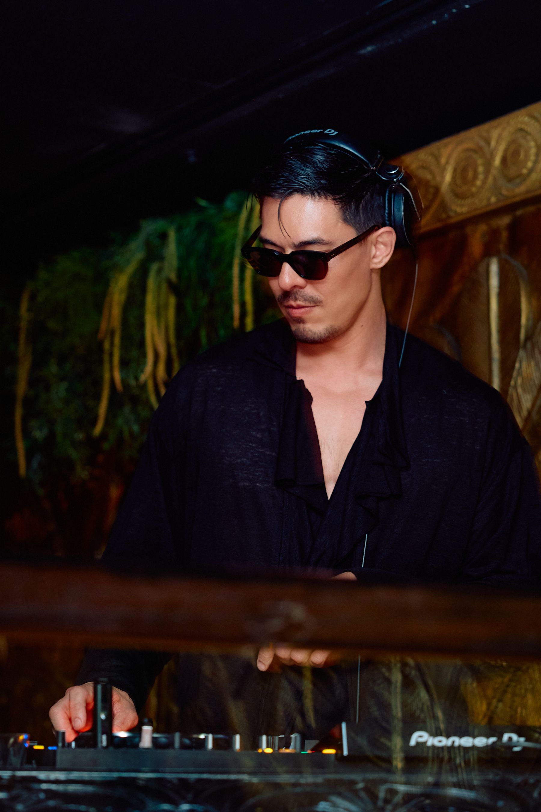 DJ music DJ in black shirt and sunglasses, working at DJ booth with DJ equipment.