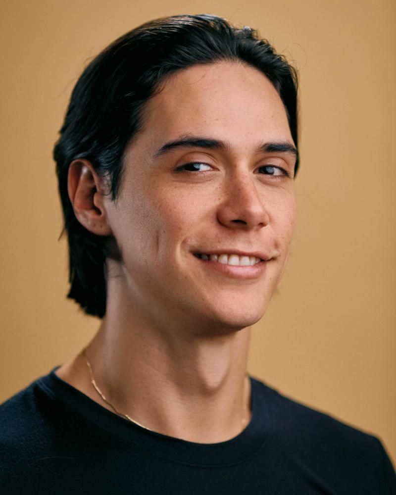 Portrait of a male model with long hair in a black studio outfit