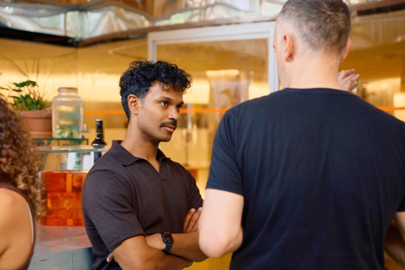Two men are talking, one with a watch on his wrist.