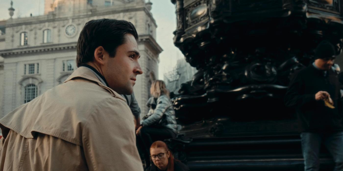 Maxim Gennett, known for his role as the lead character of "The Great Gatsby," is captured in a moment of contemplation on a city street. He is dresse
