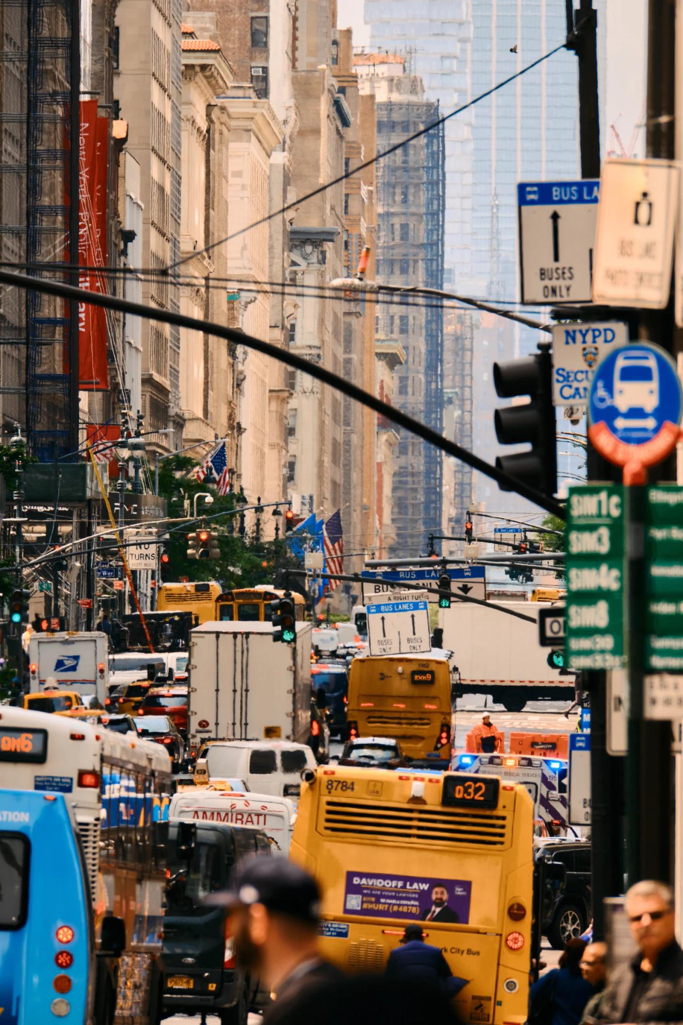 A bustling New York City street filled with vehicles, pedestrians, and tall buildings.