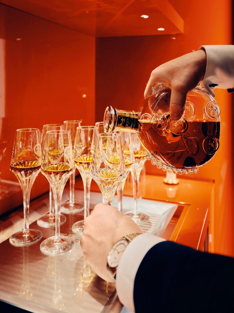 Server pouring a luxury spirit into glasses for wedding guests