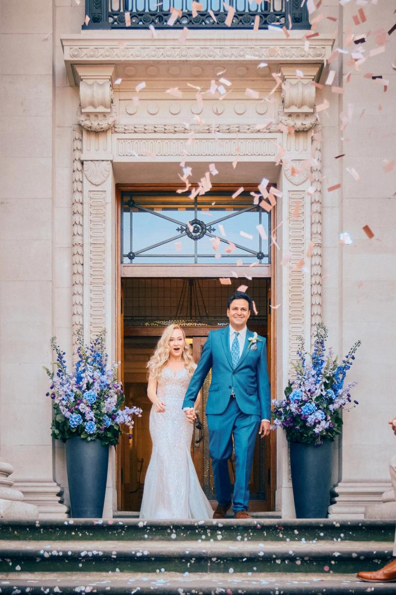 Groom in a blue suit walking up steps outside the wedding venue