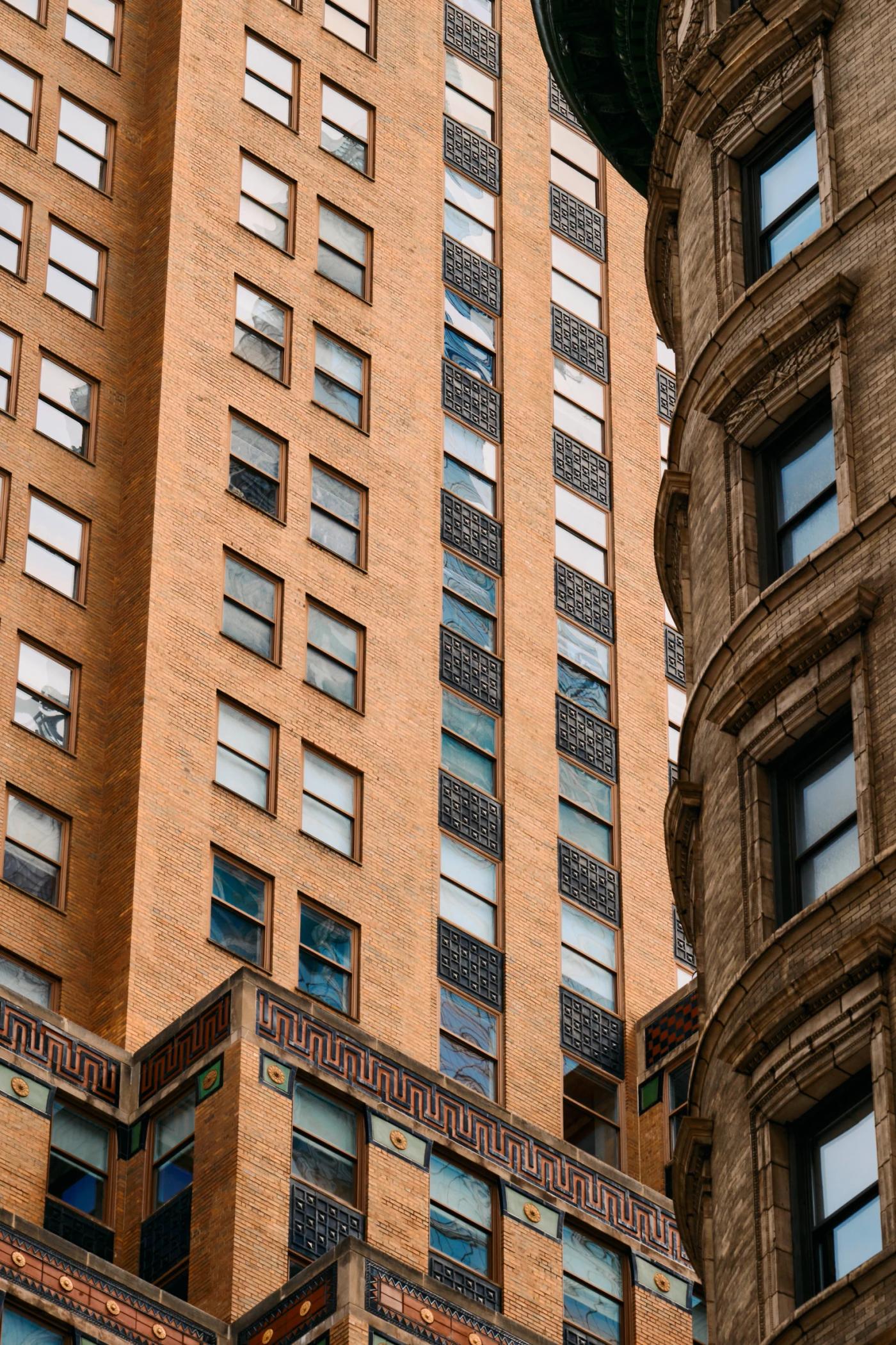 Two tall buildings with many windows, a clock on the left side, and a traffic light on the right side.