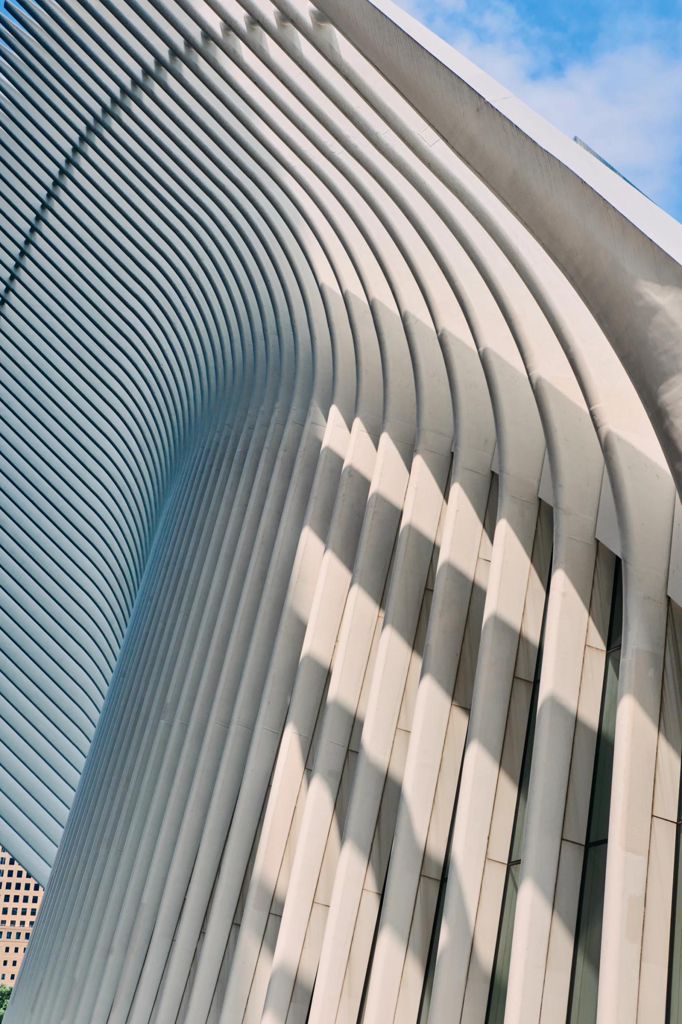 A modern, white building with curved lines and a curved roof is captured in a low-angle shot, showcasing its unique architecture.