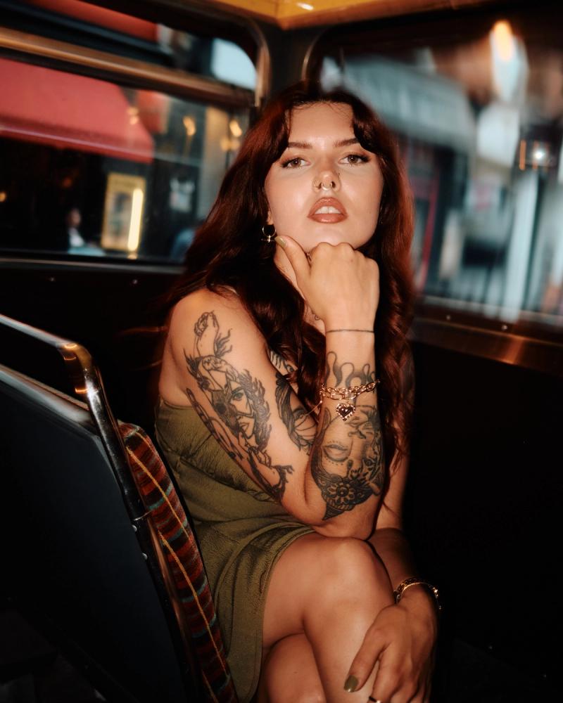 Portrait of a tattooed woman with hand on chin in a vintage interior