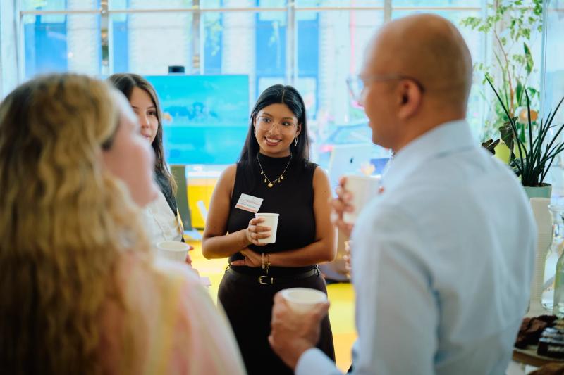 A group of people are gathered around a woman who is holding a cup.