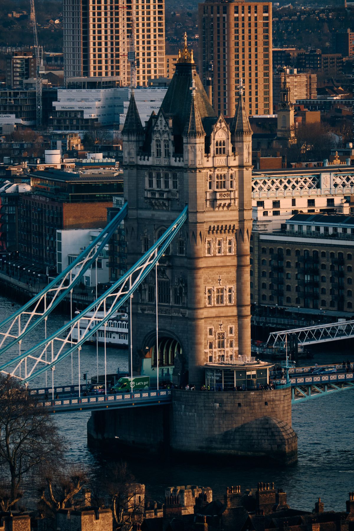 Tower Bridge London spanning the River Thames at golden hour, Victorian Gothic architecture with modern high-rise buildings in background