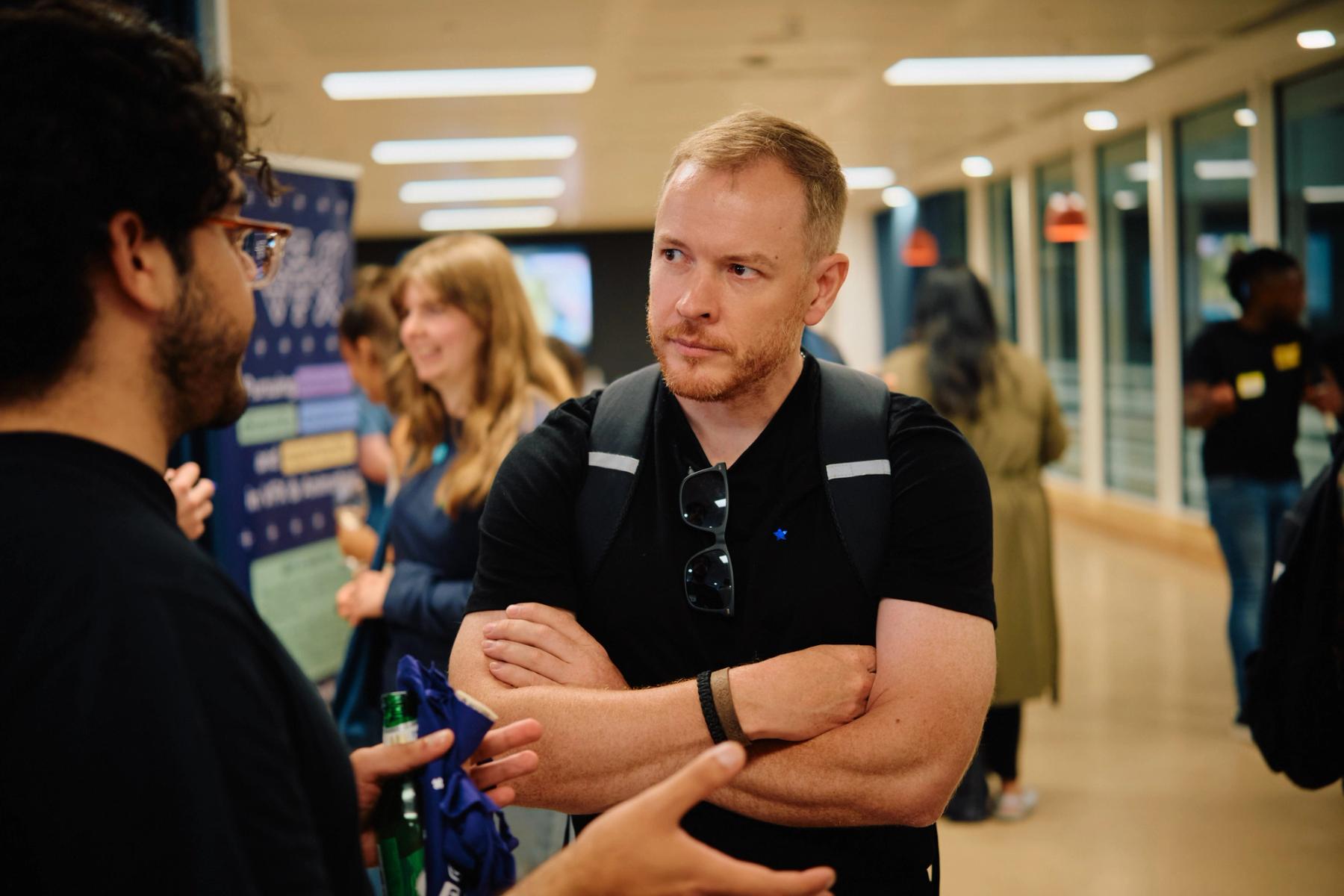 Access VFX community event 2026, man in a black polo with arms crossed talking near an ACCESS VFX banner