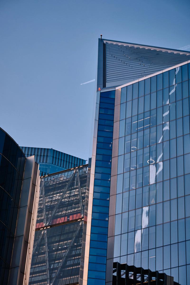 Contemporary glass and steel office buildings with reflective blue curtain wall and corrugated metal roofing, City of London architecture