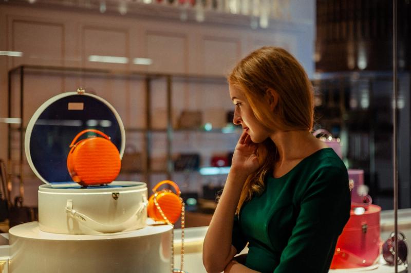Woman in a green dress looking down beside drinks in a neon-lit interior