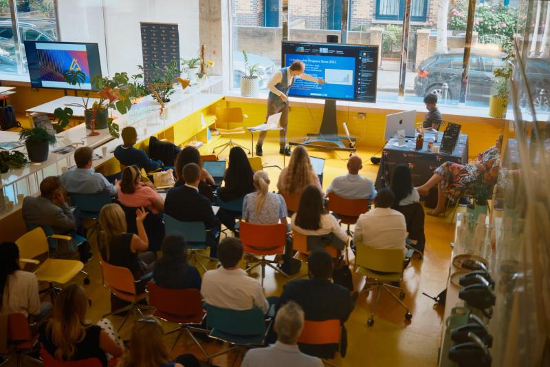 A man is standing in front of a large group of people, giving a presentation.