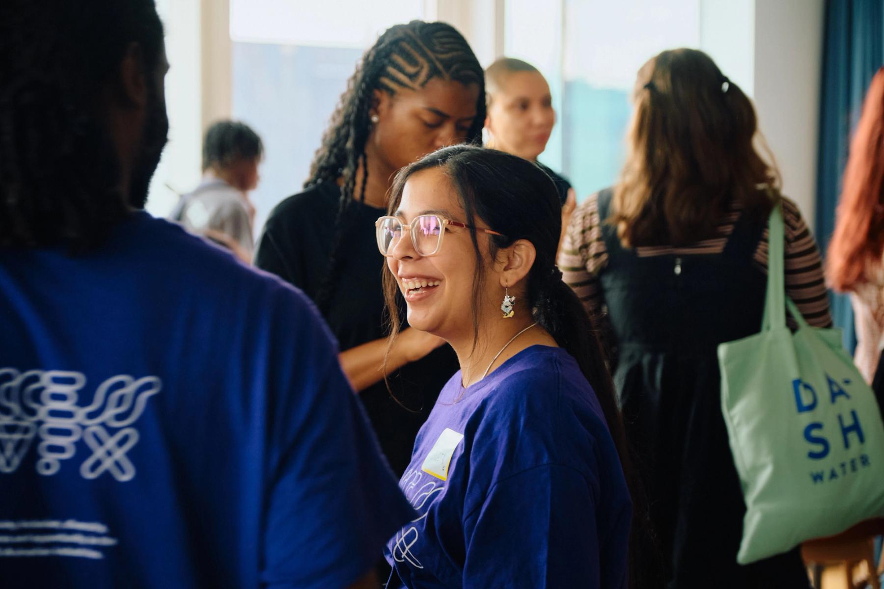 Access VFX community event 2026, smiling woman with glasses and ponytail in a purple ACCESS VFX shirt mid-conversation