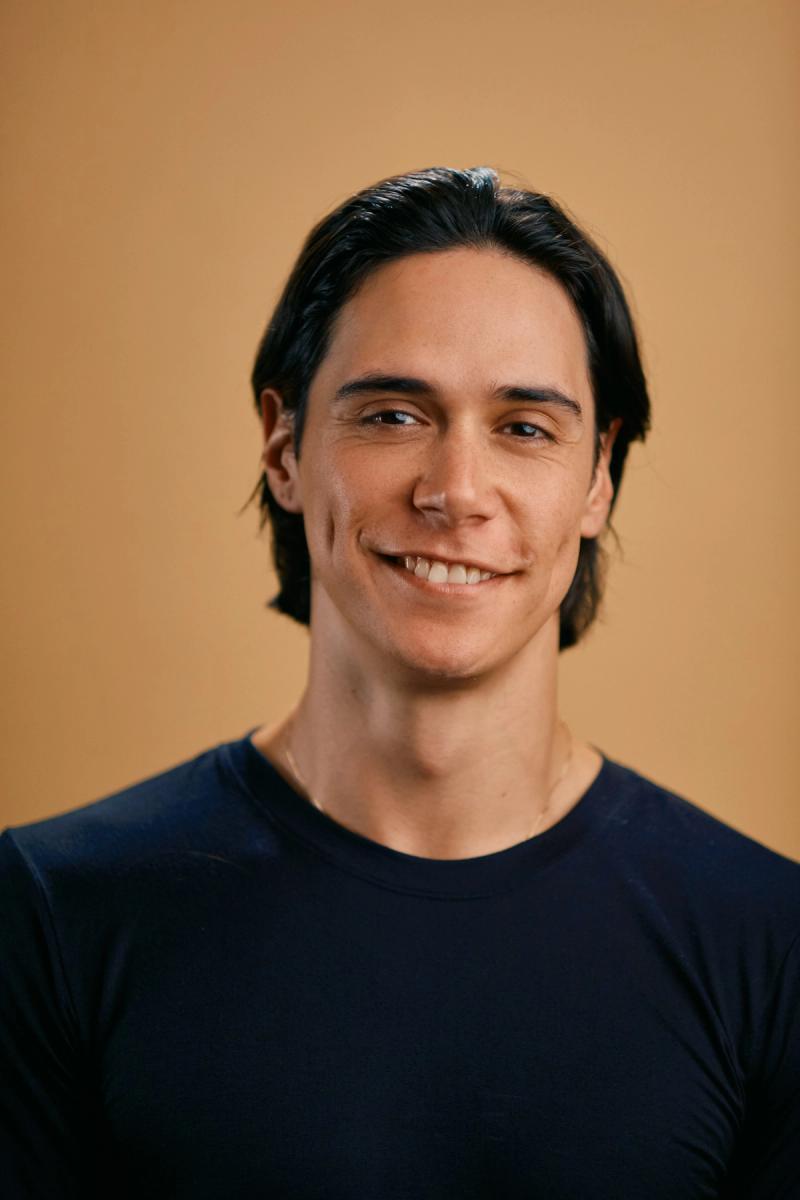 Smiling portrait of a long-haired man in a sleeveless black top