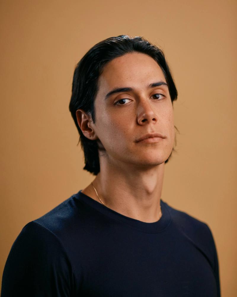 Close portrait of a long-haired man wearing a black top and chain necklace