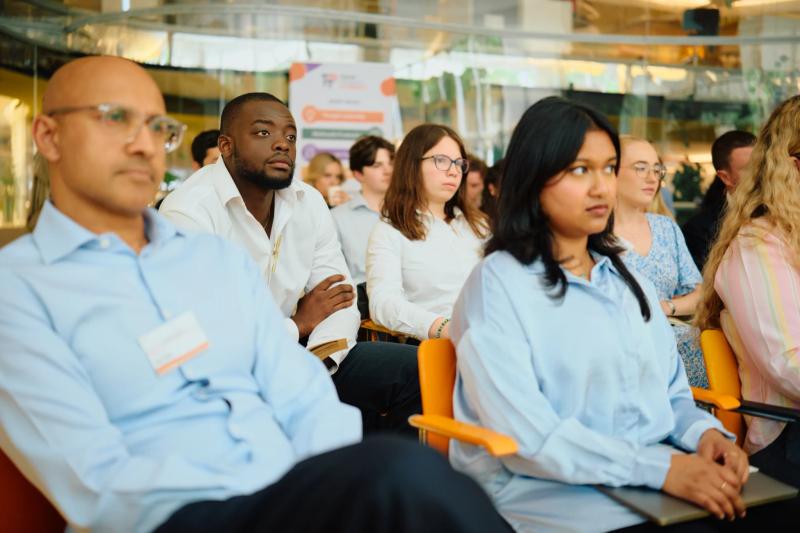 A group of people are sitting in chairs, listening to a speaker.