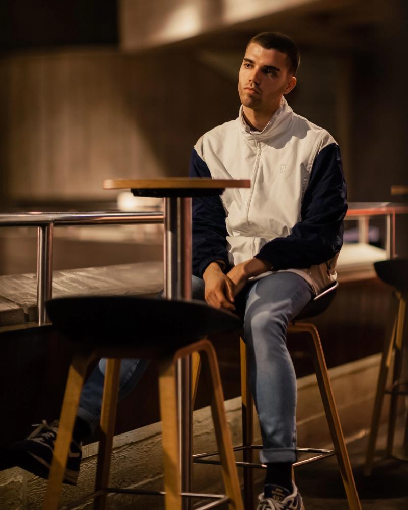 Moody portrait of a man seated in warm light near a stage-like set