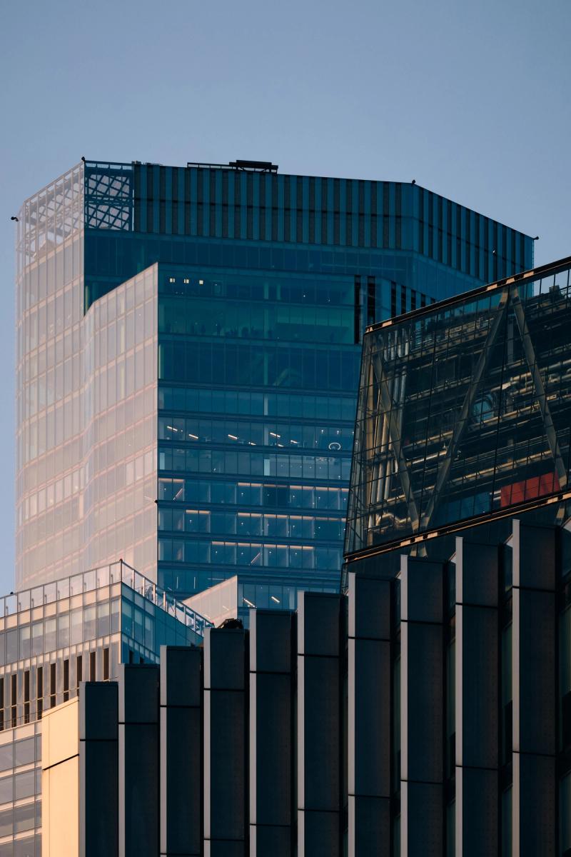 Contemporary glass and steel office buildings with teal curtain wall, horizontal louvers and black structural colonnade, City of London architecture