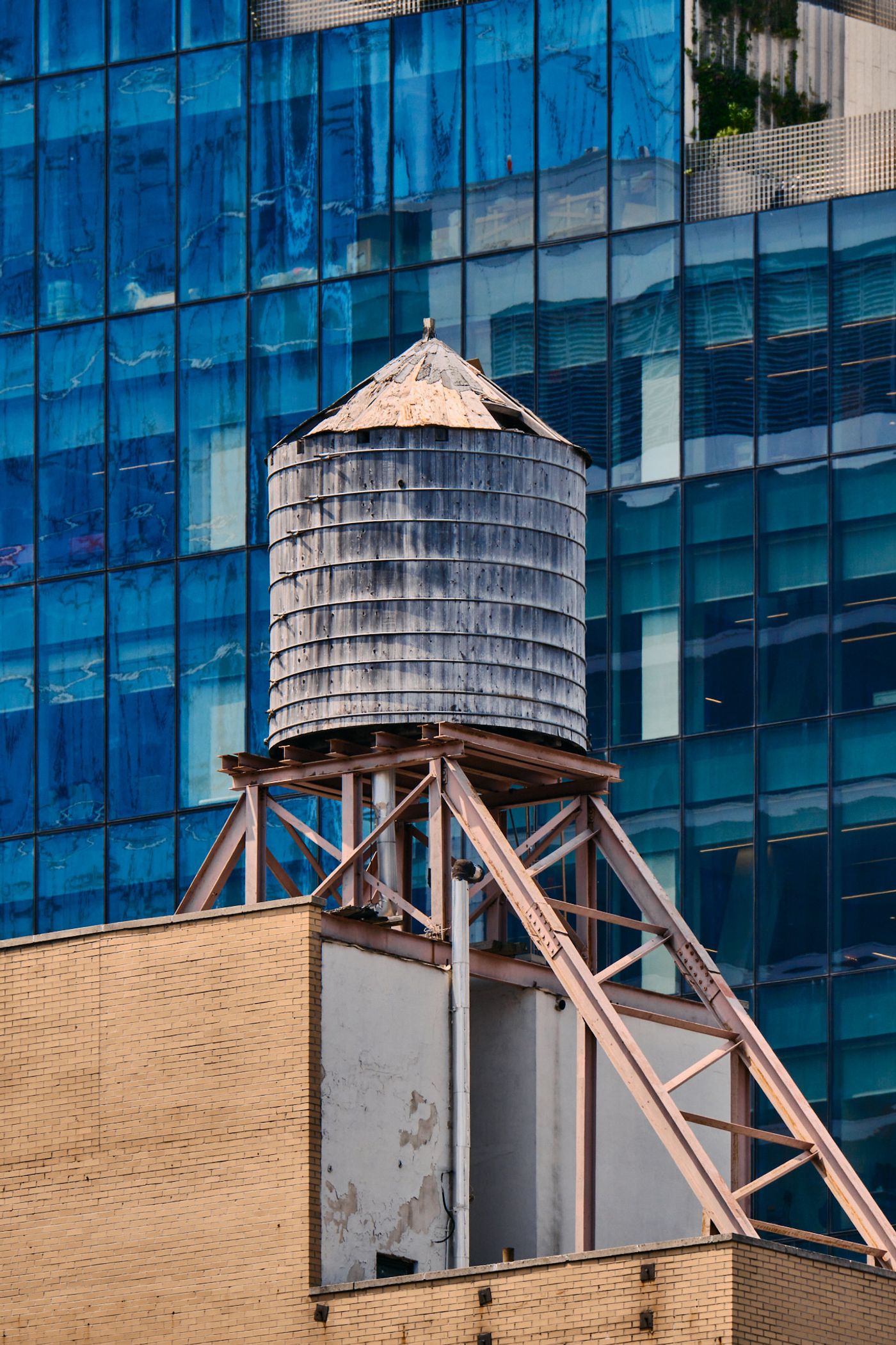Water tower in urban setting, with modern glass building in background.
