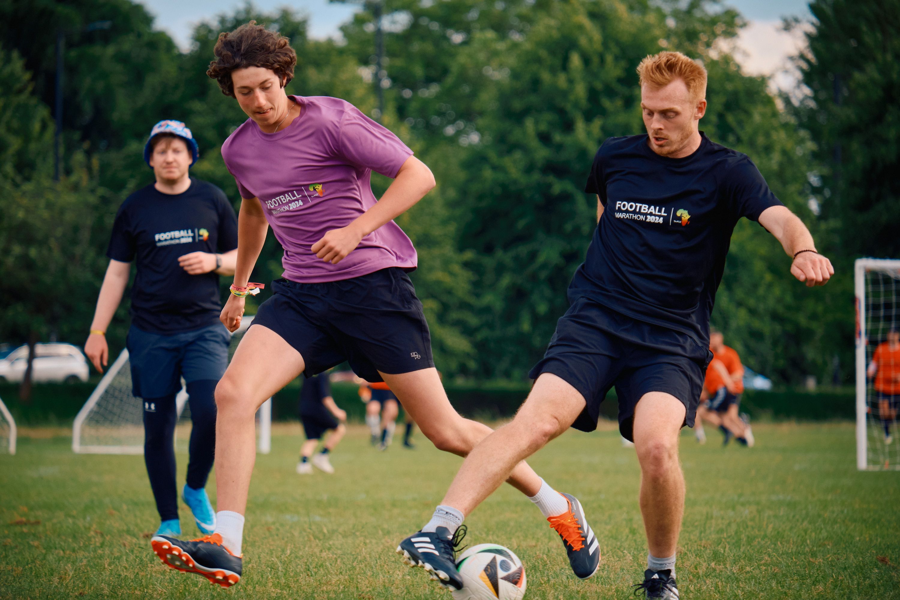 People playing football in a green field of grass in the summer