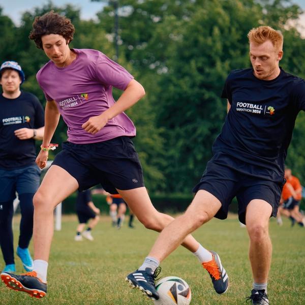 People playing football in a green field of grass in the summer