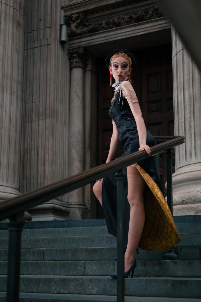 Fashion portrait of a woman posing on a staircase in a dark dress