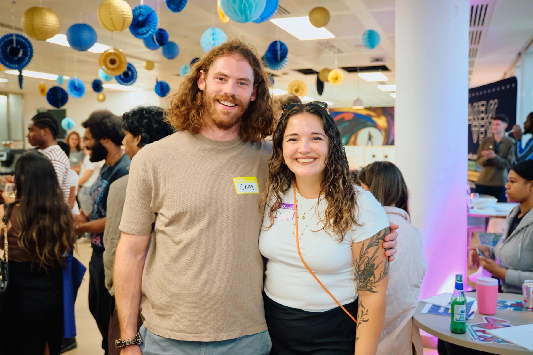 Access VFX community event 2026, Sam and a friend smiling for the camera under blue and gold paper lanterns