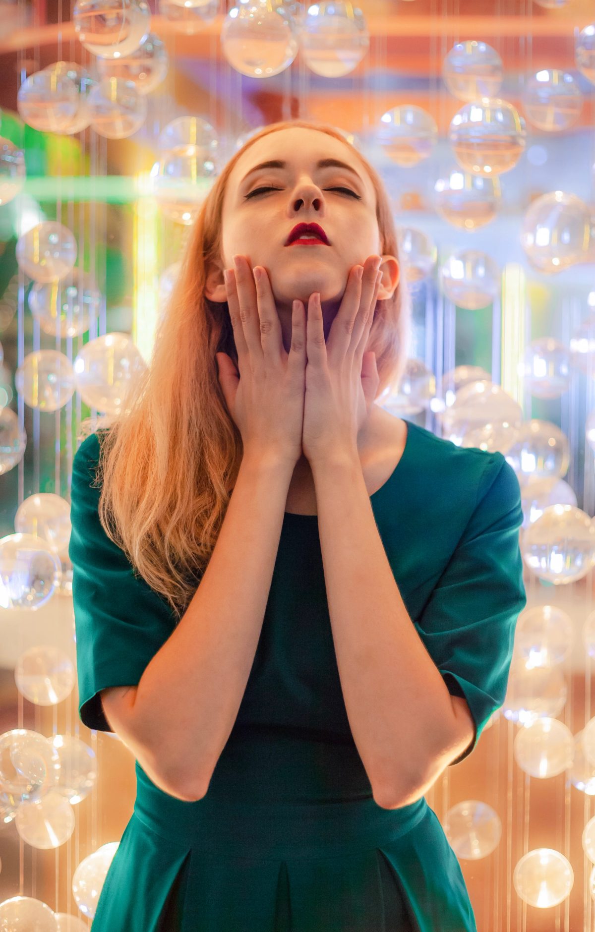 Expressive portrait of a woman in a green dress with hands raised near her face