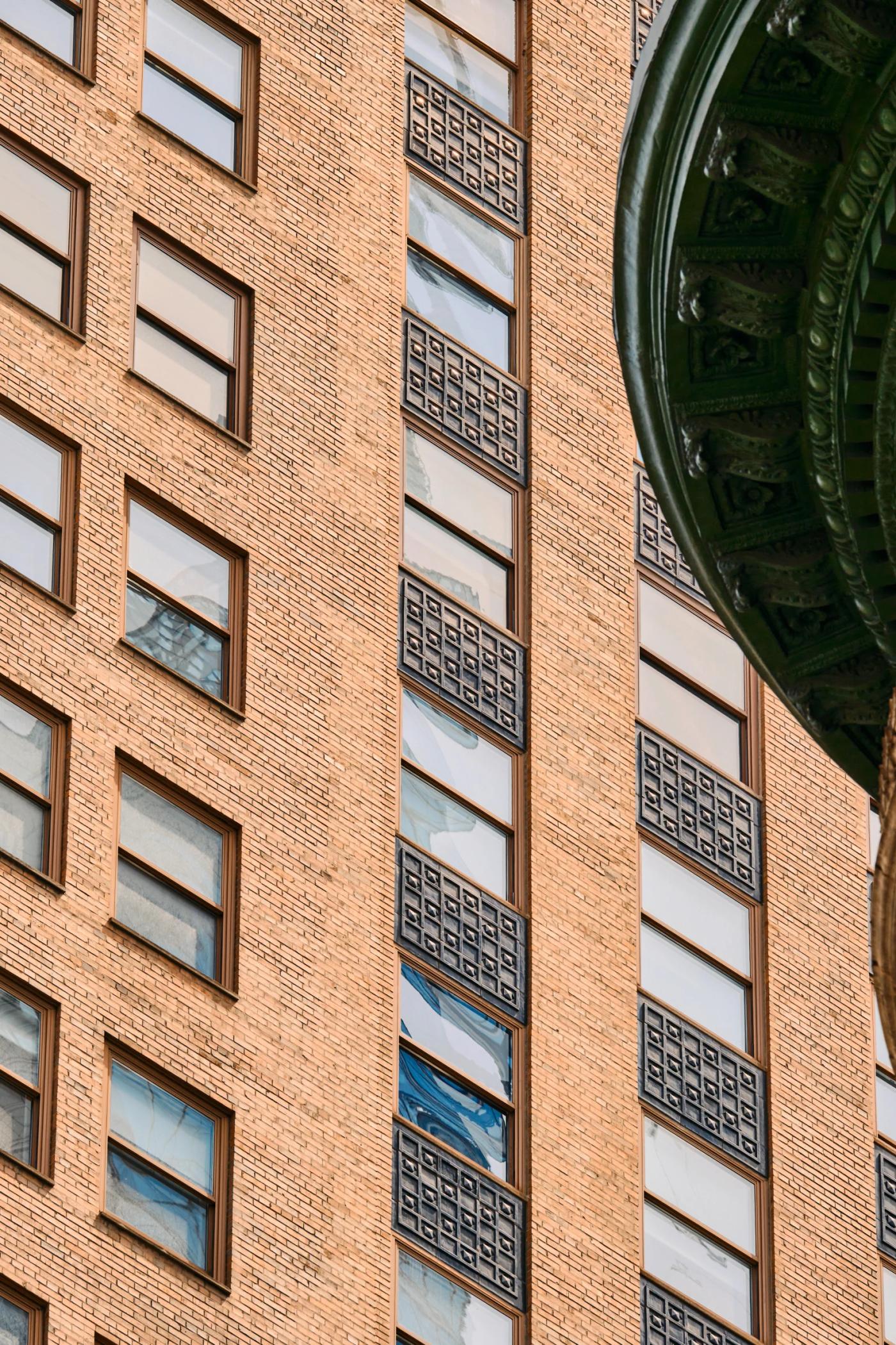 A tall brick building with a green dome and a clock on the side.