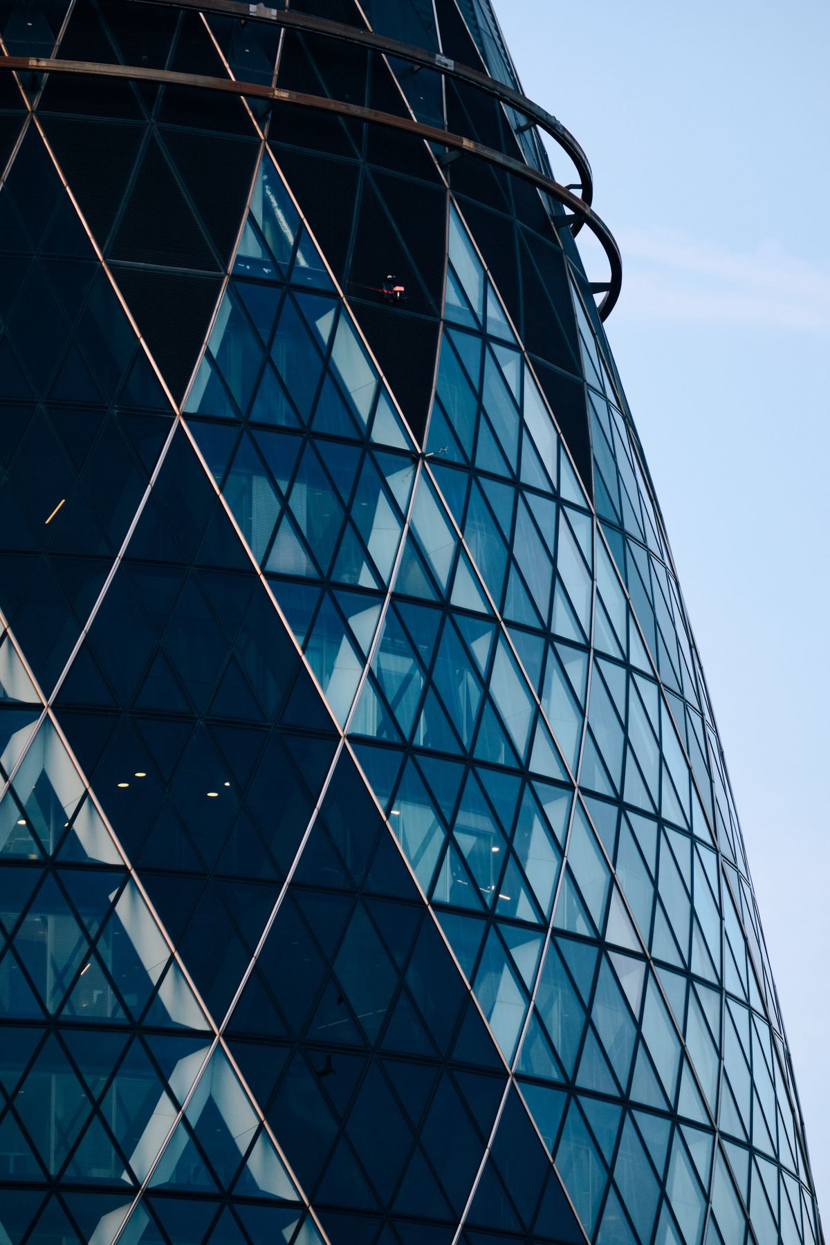 Modern mixed-use high-rise with antenna spire featuring dark teal corrugated metal facade and terracotta brick cladding, contemporary urban architecture
