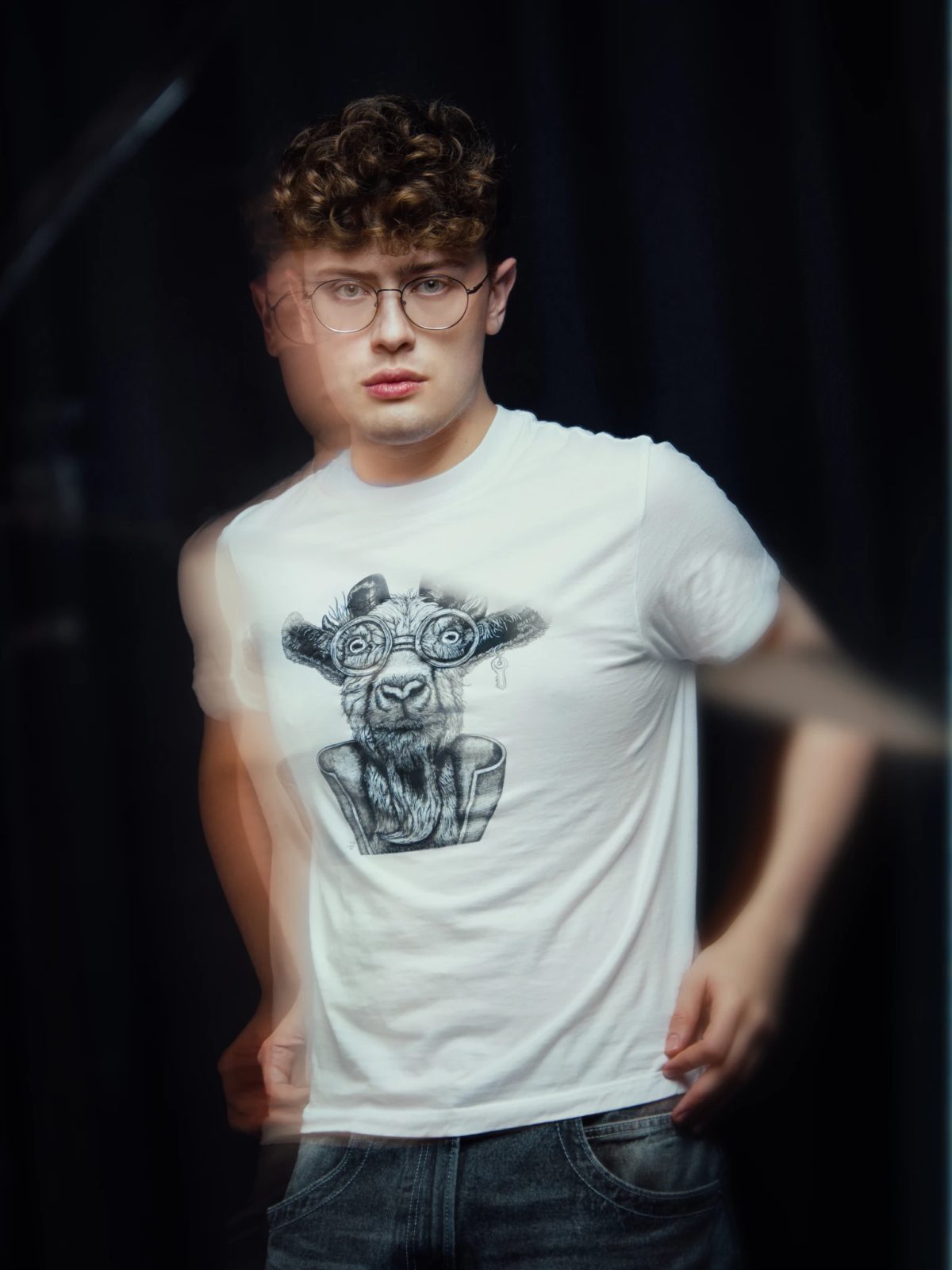 A man wearing glasses and a white shirt with a cow on it.