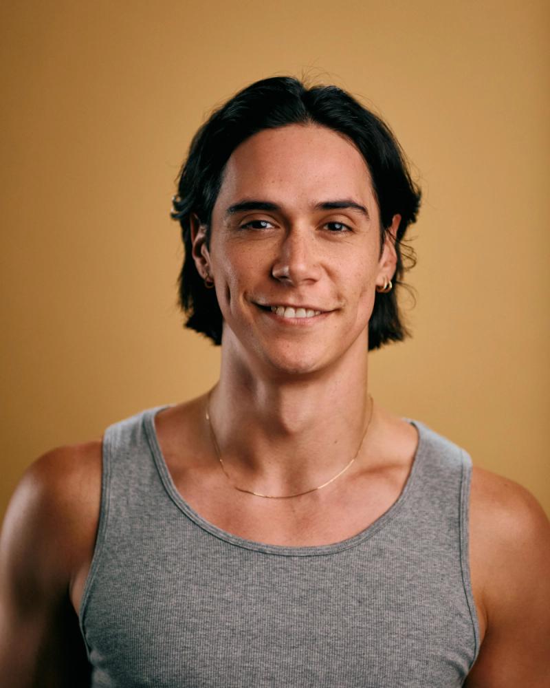 Fashion portrait of a long-haired man in a black mesh top with hand near face