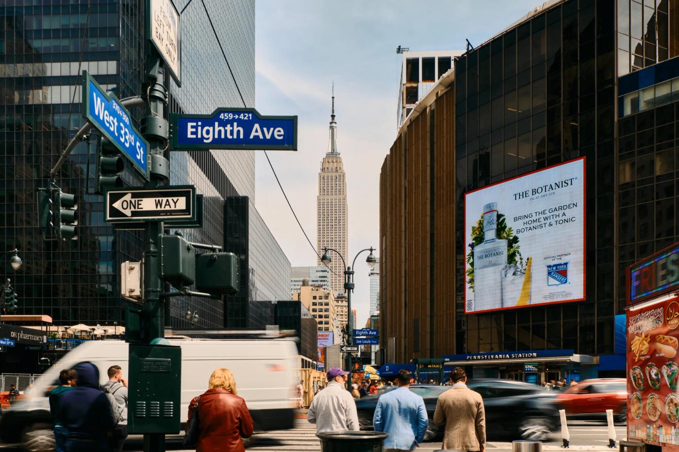 A bustling New York City street scene features towering buildings, a busy intersection, and a variety of vehicles.