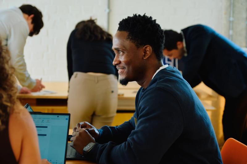 A man is sitting at a table with a laptop.