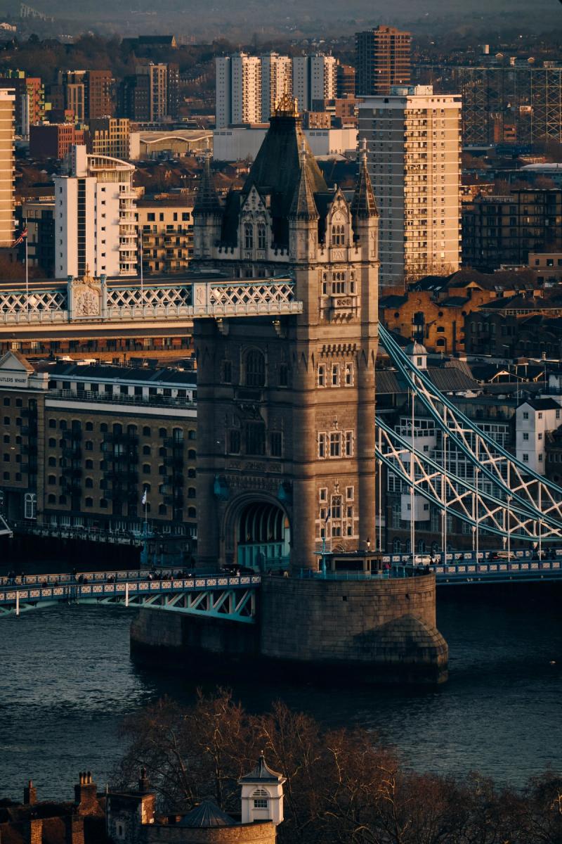 Tower Bridge spanning the River Thames at golden hour, Victorian Gothic Revival stone towers with suspension cables and London skyline