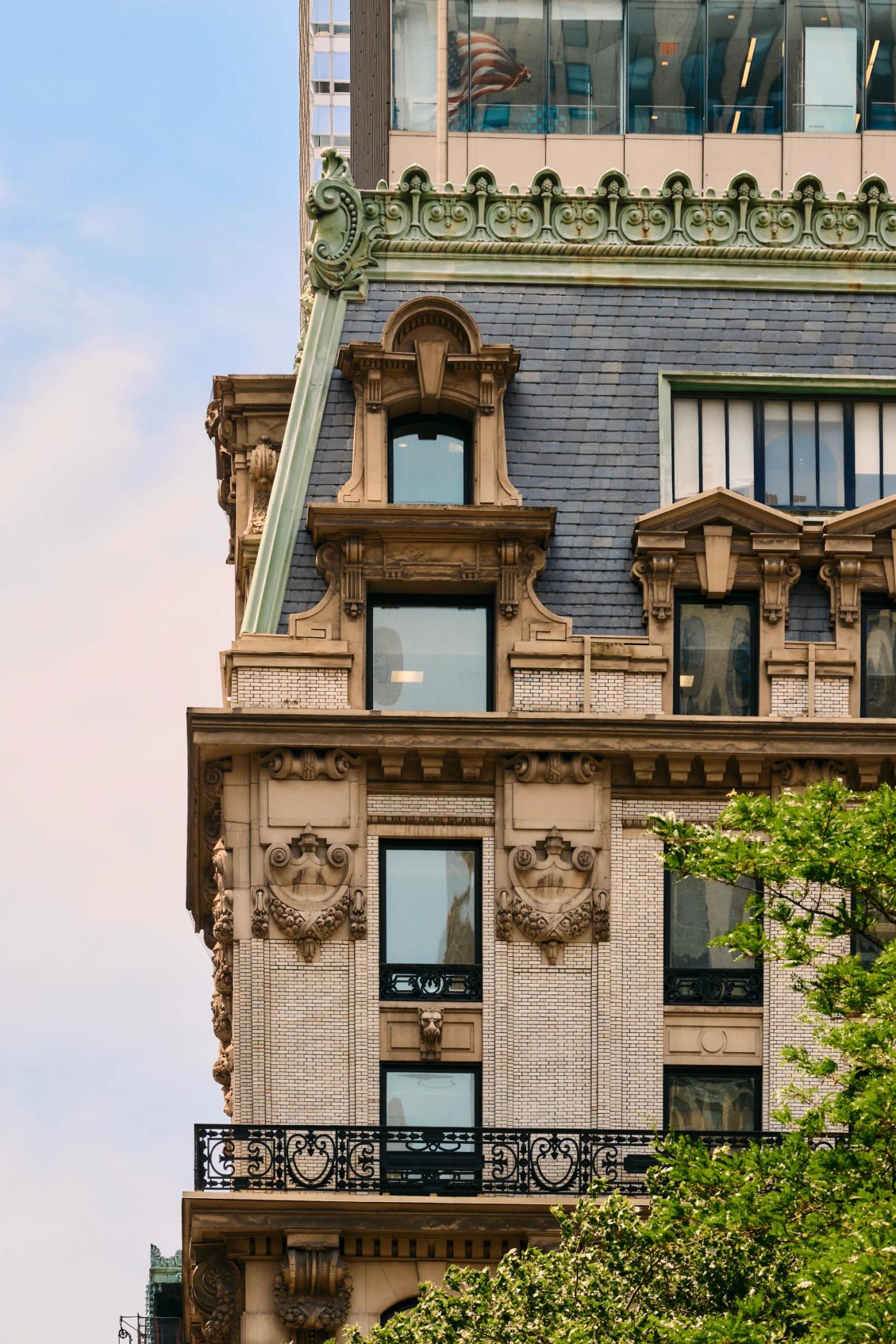 A grand, ornate building with intricate details and a black roof stands tall against a clear blue sky.