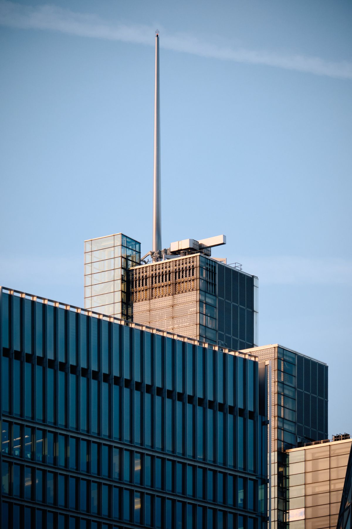 Modern mixed-use high-rise with terracotta brick base and pastel glass curtain wall upper section, contemporary urban architecture against clear blue sky